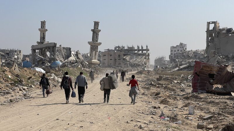 Destruction in Gaza. People walk towards destroyed buildings.