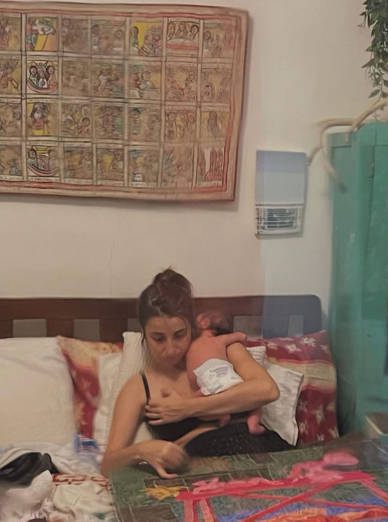 Artist Talia Levitt paints with her newborn resting on her shoulder—a glimpse into the intimate reality behind ‘24/7,’ the body of work shaped in the blur between caregiving and studio practice. Photo courtesy of the artist.